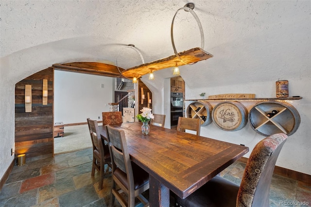 34 Amaranth Dr, Littleton, CO 80127 - dining area featuring arched walkways, baseboards, stone tile flooring, and lofted ceiling