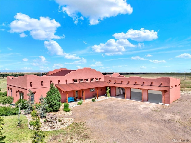 5549 Yulle Rd, Bennett, CO 80102 - adobe home with driveway, stucco siding, a garage, and covered porch