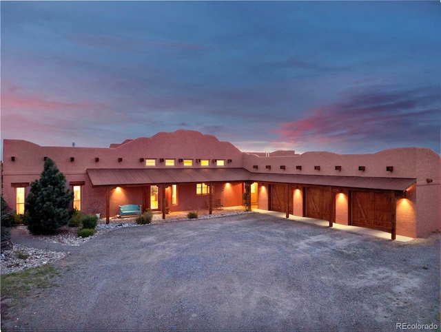 5549 Yulle Rd, Bennett, CO 80102 - pueblo-style house featuring driveway, stucco siding, a porch, and a garage