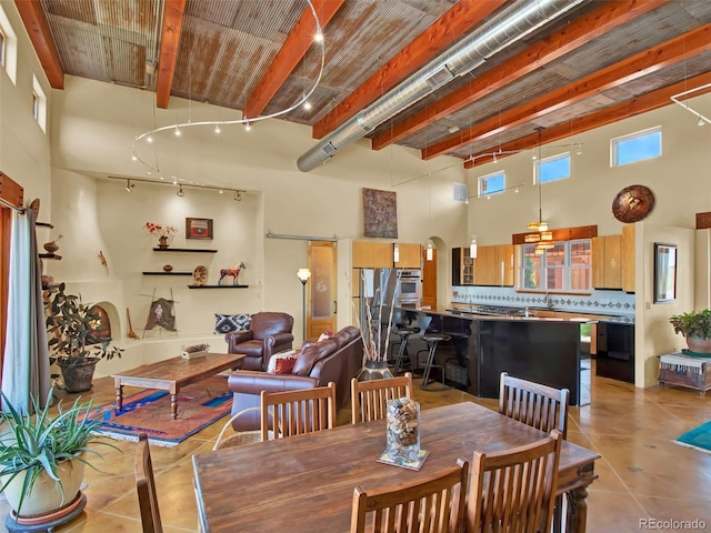 5549 Yulle Rd, Bennett, CO 80102 - dining space with light tile patterned floors, a high ceiling, arched walkways, and beam ceiling
