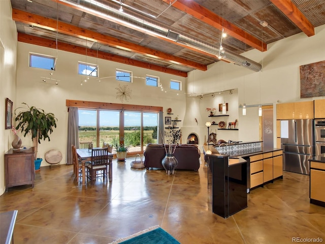 5549 Yulle Rd, Bennett, CO 80102 - kitchen featuring a towering ceiling, beamed ceiling, stainless steel appliances, dark countertops, and open floor plan