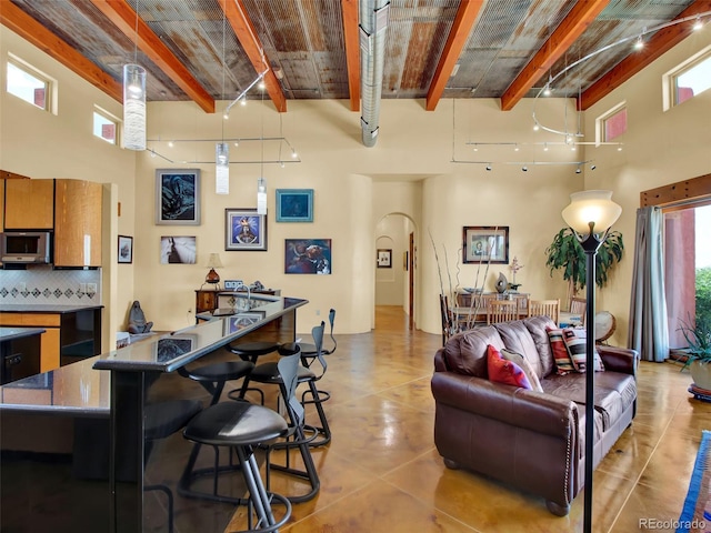 5549 Yulle Rd, Bennett, CO 80102 - living area featuring beamed ceiling, a high ceiling, and arched walkways