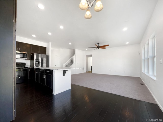 1826 Sunshine Ave, Longmont, CO 80504 - kitchen with stainless steel appliances, a ceiling fan, dark wood-type flooring, a breakfast bar, and dark brown cabinets