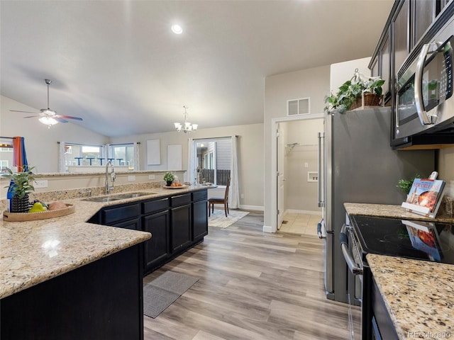 kitchen with lofted ceiling, light wood-style flooring, light stone countertops, stainless steel appliances, and a sink