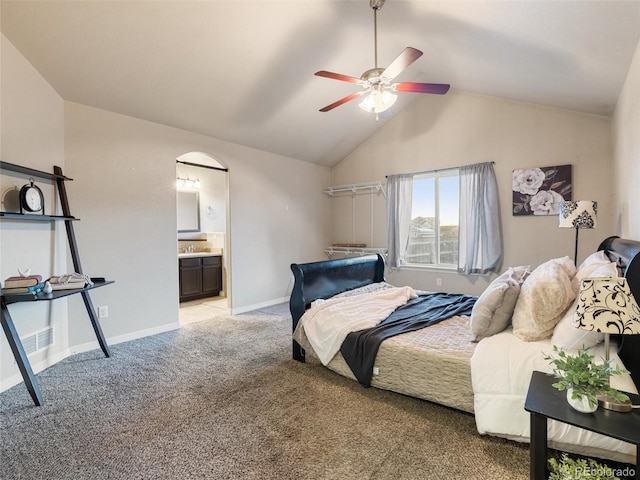 bedroom with light colored carpet, connected bathroom, vaulted ceiling, a sink, and baseboards