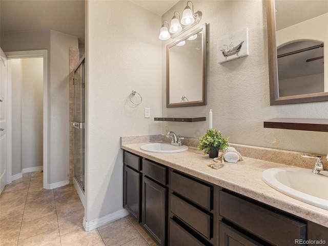 full bath with double vanity, a stall shower, tile patterned flooring, and a sink