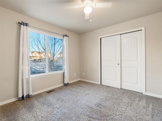 unfurnished bedroom with baseboards, visible vents, a ceiling fan, carpet floors, and a closet