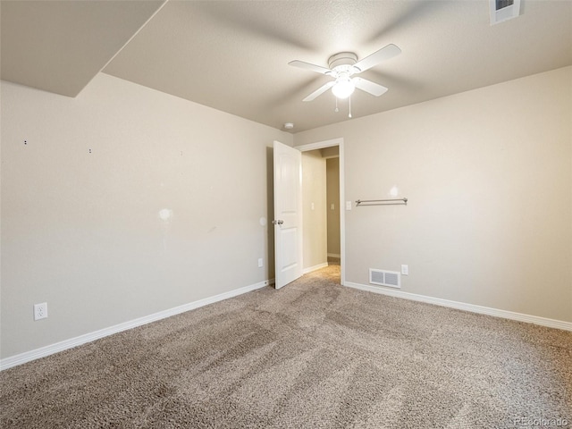 spare room with light colored carpet, visible vents, ceiling fan, and baseboards