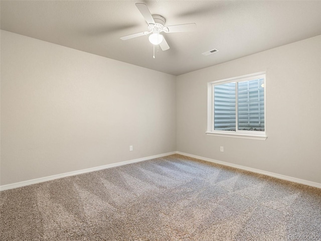 carpeted spare room with visible vents, ceiling fan, and baseboards