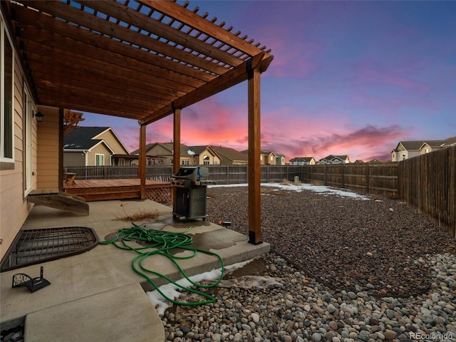 patio terrace at dusk with a fenced backyard and a pergola