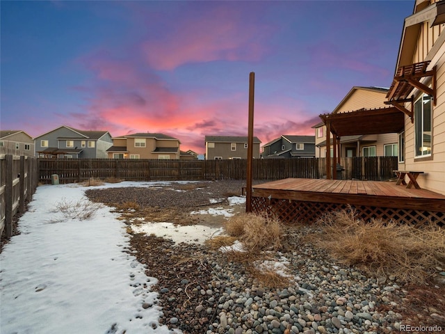 yard covered in snow featuring a residential view, a fenced backyard, and a deck