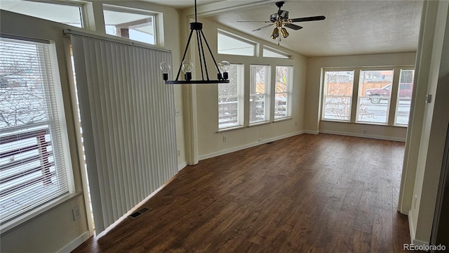 interior space featuring dark wood-style flooring, visible vents, vaulted ceiling, a textured ceiling, and baseboards