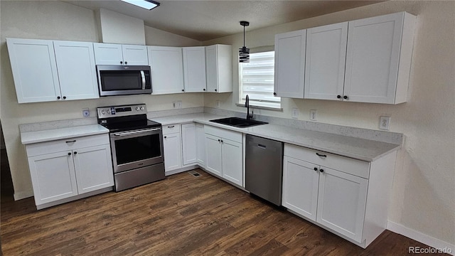 kitchen featuring dark wood finished floors, appliances with stainless steel finishes, white cabinets, vaulted ceiling, and a sink