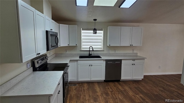 kitchen with white cabinets, dark wood-style floors, appliances with stainless steel finishes, light countertops, and a sink