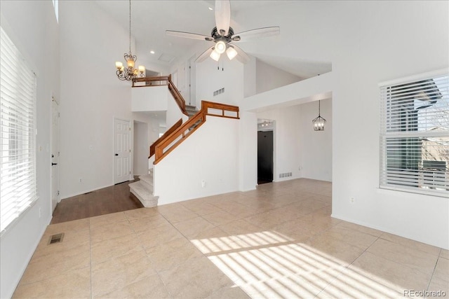 unfurnished living room featuring a wealth of natural light, visible vents, and ceiling fan with notable chandelier