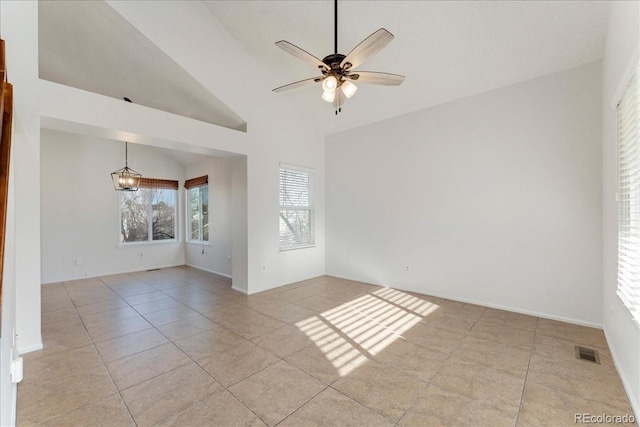 empty room featuring baseboards, visible vents, lofted ceiling, light tile patterned flooring, and ceiling fan