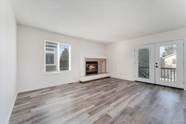 unfurnished living room with french doors, plenty of natural light, a textured ceiling, and wood finished floors