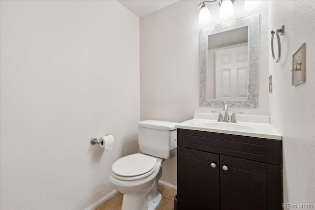 half bathroom with tile patterned floors, baseboards, toilet, and vanity