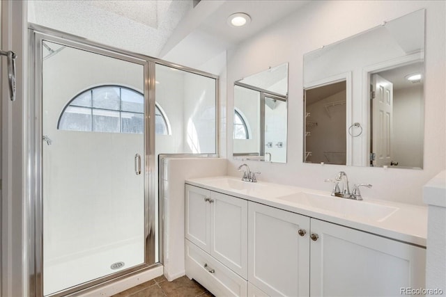 bathroom with double vanity, a stall shower, and a sink