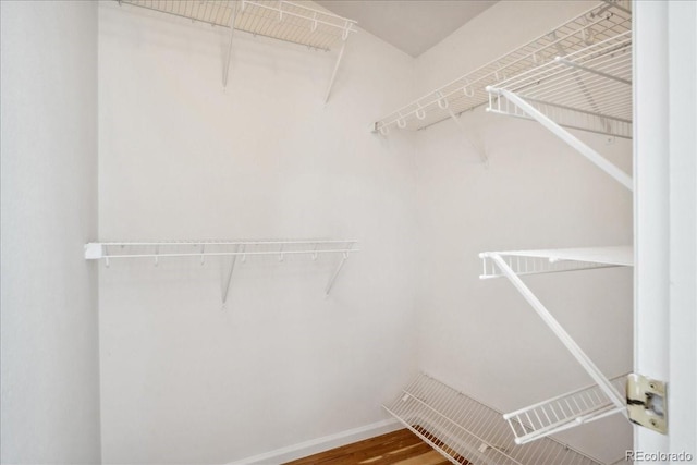 walk in closet with wood finished floors