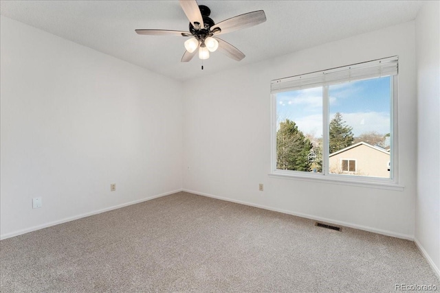 carpeted empty room featuring visible vents, baseboards, and a ceiling fan