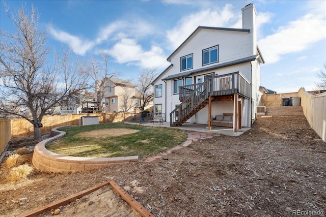 rear view of house featuring a deck, a fenced backyard, stairway, a chimney, and a patio area