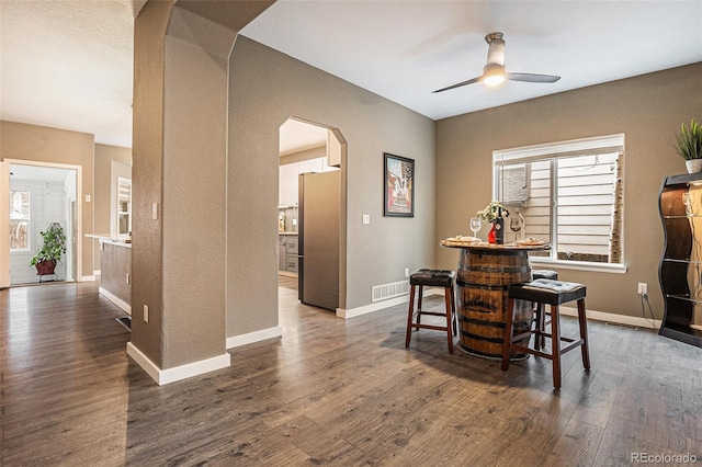 dining area with baseboards, visible vents, arched walkways, dark wood finished floors, and ceiling fan