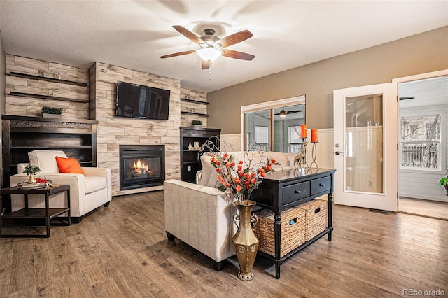 living room featuring a fireplace, wood finished floors, and a ceiling fan