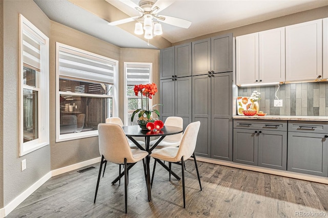 dining space featuring a textured wall, visible vents, light wood-style floors, a ceiling fan, and baseboards