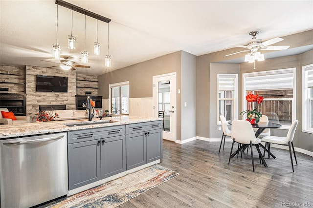 kitchen featuring a ceiling fan, dishwasher, wood finished floors, gray cabinets, and a sink