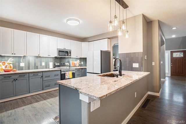 kitchen featuring stainless steel appliances, visible vents, gray cabinetry, a sink, and a peninsula