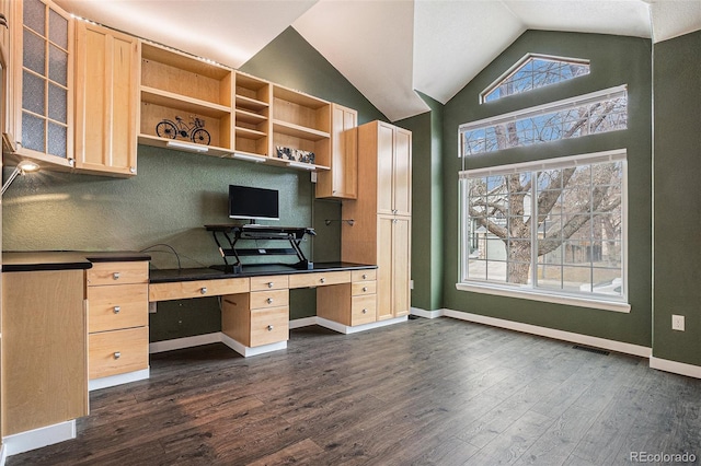 unfurnished office featuring vaulted ceiling, dark wood-type flooring, built in study area, and baseboards