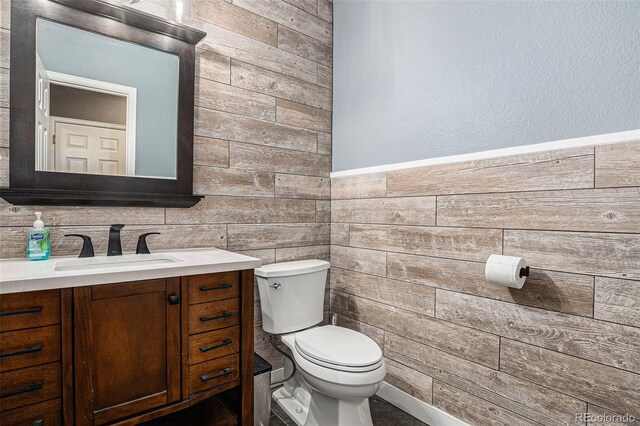 bathroom with wooden walls, vanity, and toilet