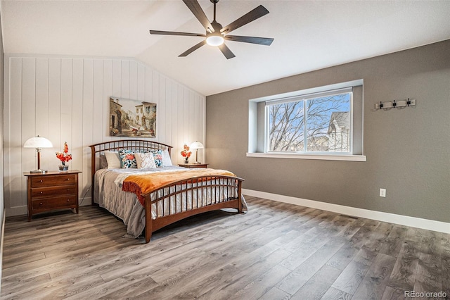 bedroom featuring a ceiling fan, baseboards, vaulted ceiling, and wood finished floors