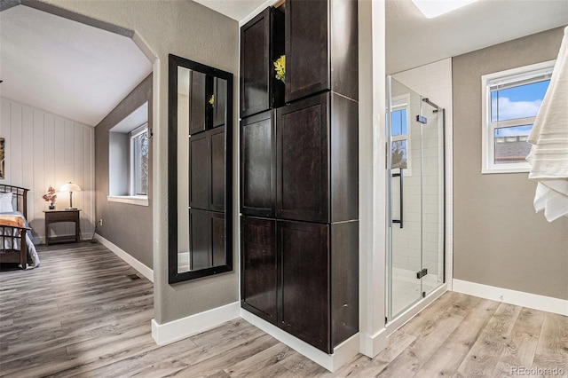 full bathroom featuring a shower stall, baseboards, and wood finished floors