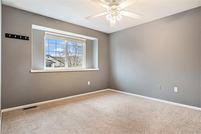 carpeted empty room featuring baseboards, visible vents, and a ceiling fan