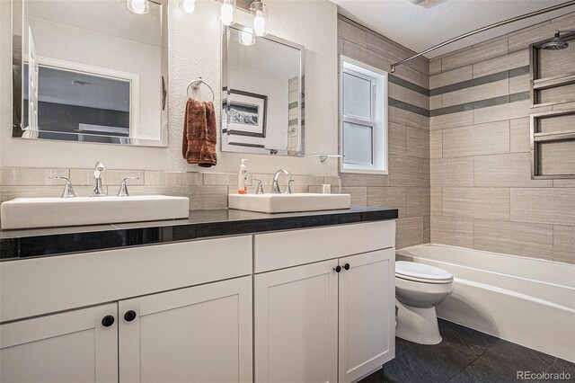 full bathroom with toilet, shower / bath combination, double vanity, and a sink