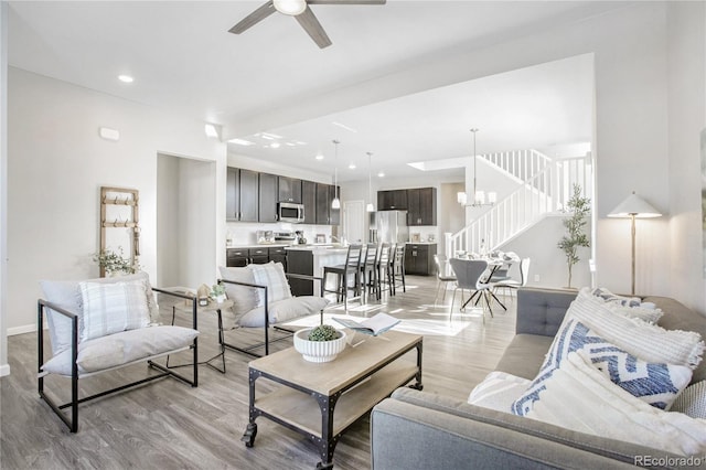 living room featuring ceiling fan with notable chandelier and light hardwood / wood-style floors