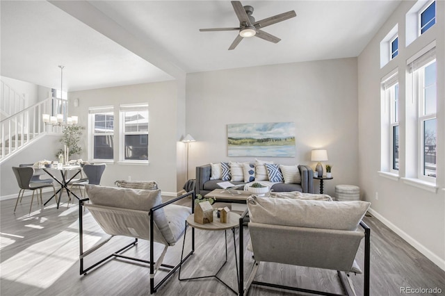 living room featuring wood-type flooring, ceiling fan with notable chandelier, and a wealth of natural light