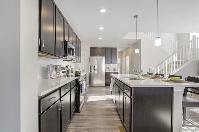 kitchen featuring pendant lighting, sink, appliances with stainless steel finishes, a kitchen island with sink, and a kitchen breakfast bar