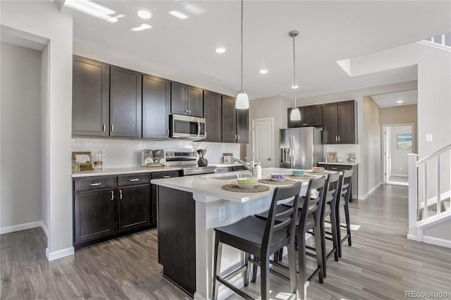 kitchen featuring a breakfast bar, stainless steel appliances, light countertops, decorative backsplash, and a sink