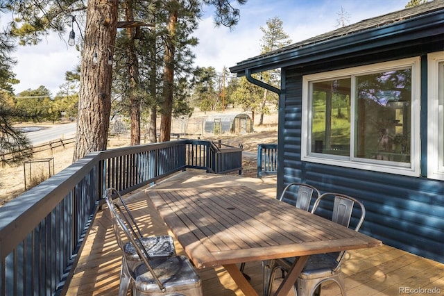 wooden deck featuring an outbuilding, a storage shed, and outdoor dining area