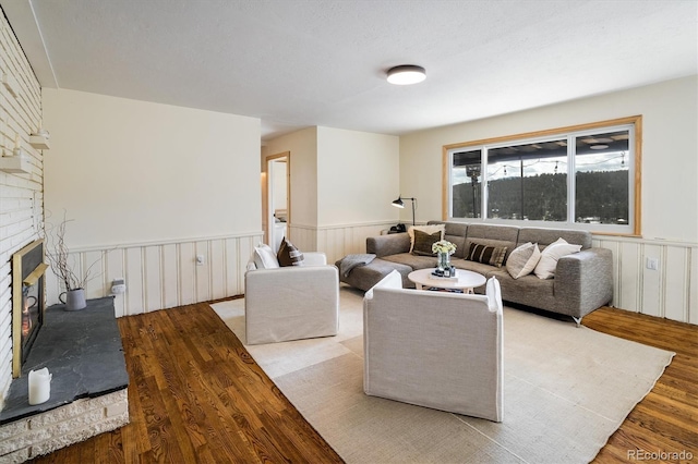 living room featuring wainscoting, a fireplace, and wood finished floors