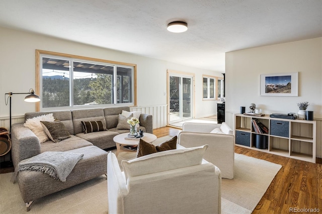 living room featuring a textured ceiling, wainscoting, and wood finished floors