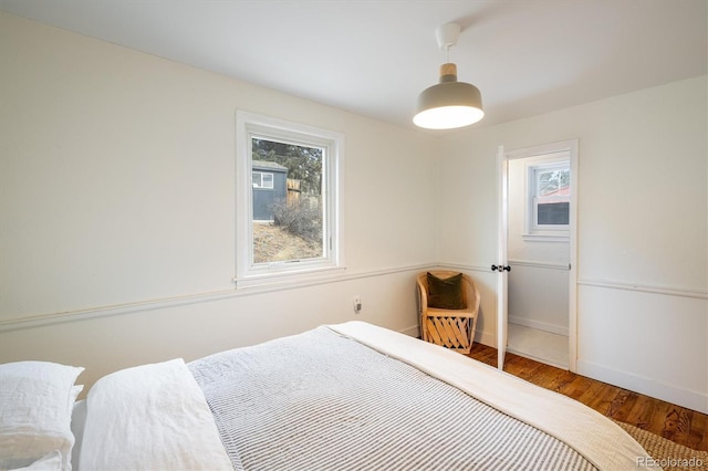 bedroom with multiple windows, wood finished floors, and baseboards