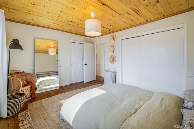 bedroom with ornamental molding, dark wood finished floors, wood ceiling, and multiple closets