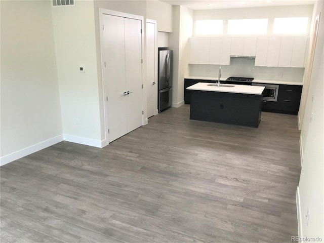 2865 W 24th Ave, Denver, CO 80211 - kitchen with stainless steel appliances, a center island with sink, white cabinetry, light countertops, and wood finished floors