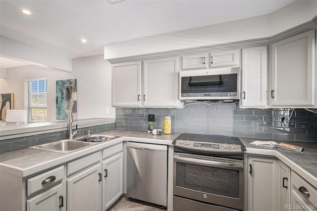 2882 W Long Cir Unit H, Littleton, CO 80120 - kitchen featuring appliances with stainless steel finishes, decorative backsplash, a peninsula, recessed lighting, and gray cabinetry