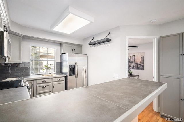2882 W Long Cir Unit H, Littleton, CO 80120 - kitchen with stainless steel appliances, gray cabinets, decorative backsplash, light wood finished floors, and a peninsula