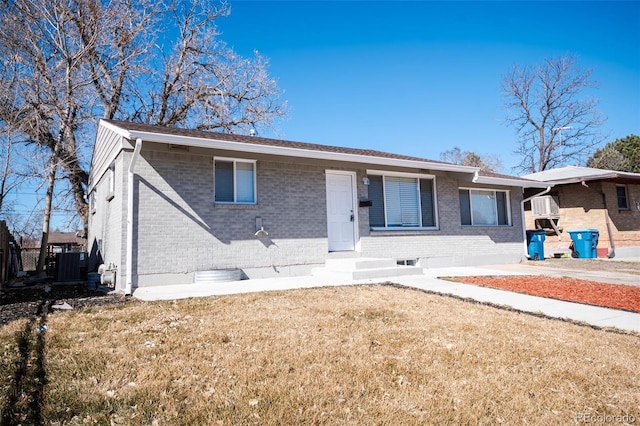 view of front of home with a front yard, central AC, and brick siding